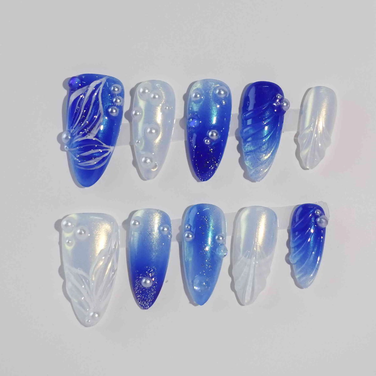 Medium almond-shaped blue press on nails with pearl white gradients, seashells, and angel wing details.