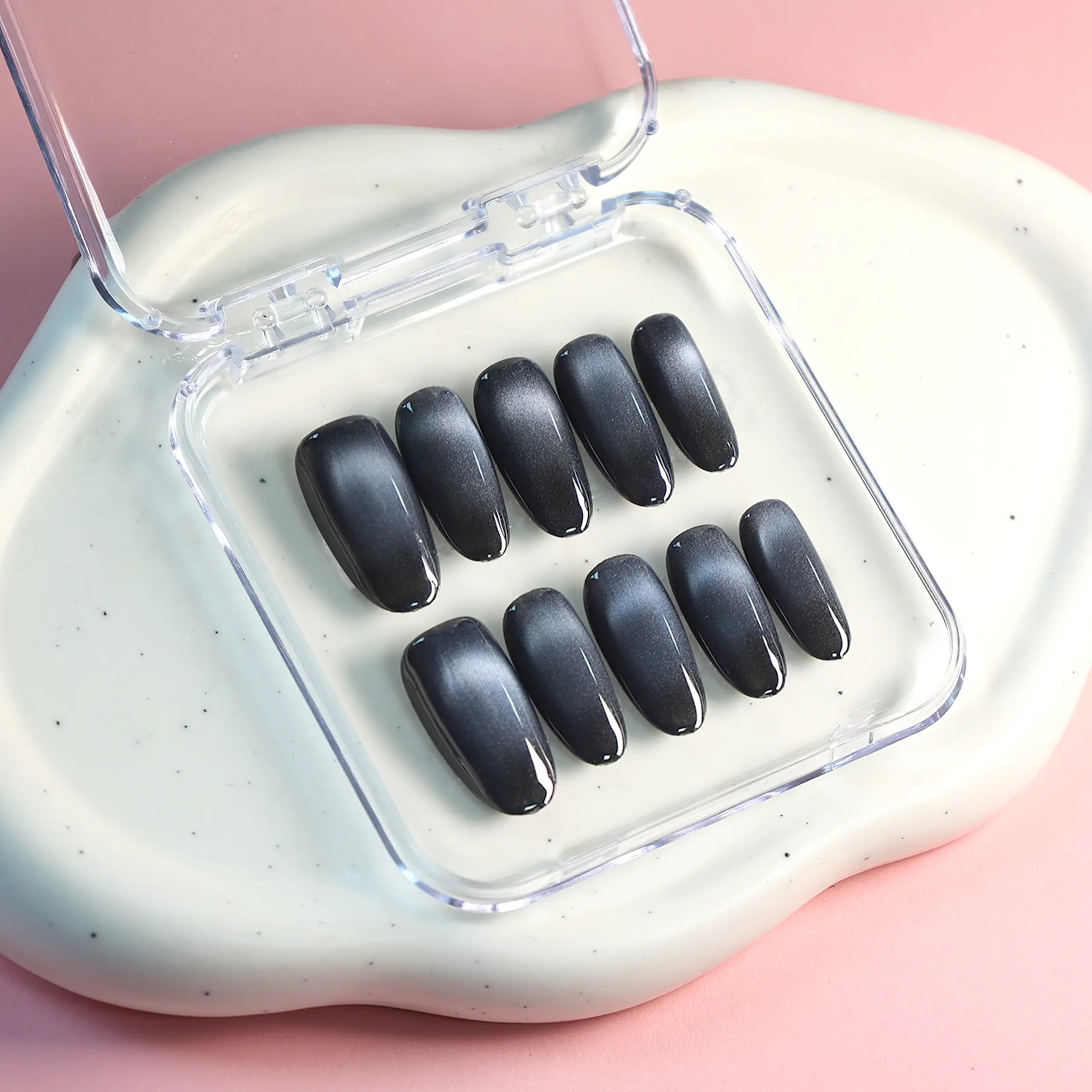 Flat lay of black press-on nails with nail art box