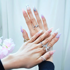 Close-up of glossy nails with iridescent chrome finish, soft color gradient, and sparkling rhinestones