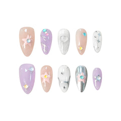 Almond-shaped pink and lilac press on nails with chrome accents, rhinestones, and pastel stars.