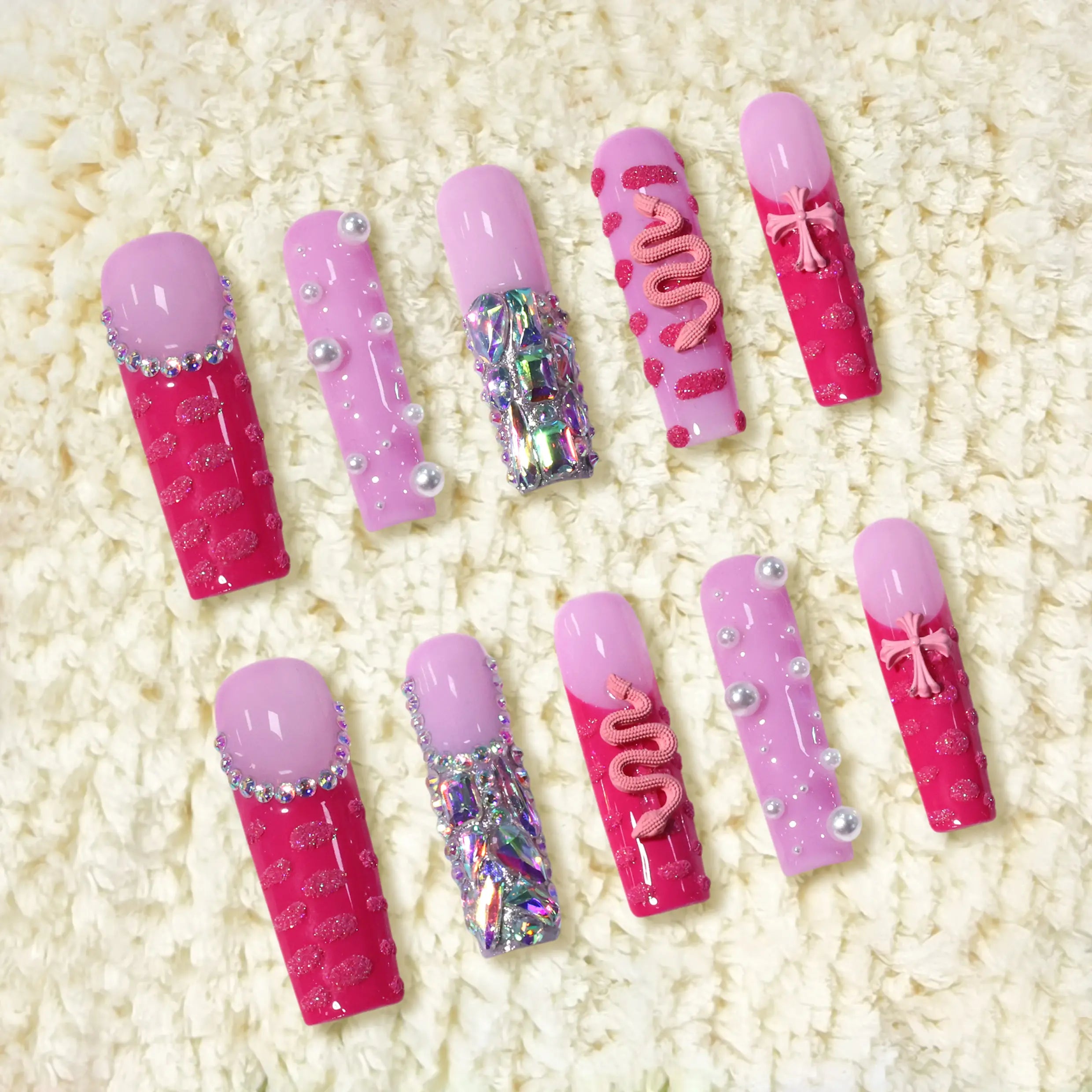 Extra long coffin-shaped pink press-on nails featuring rhinestones, 3D bows, pearls, and glitter snake art on hot and pastel pink bases
