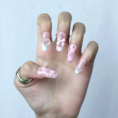 Hand model wearing pink coffin nails with sculpted white 3D flowers and delicate pearl details