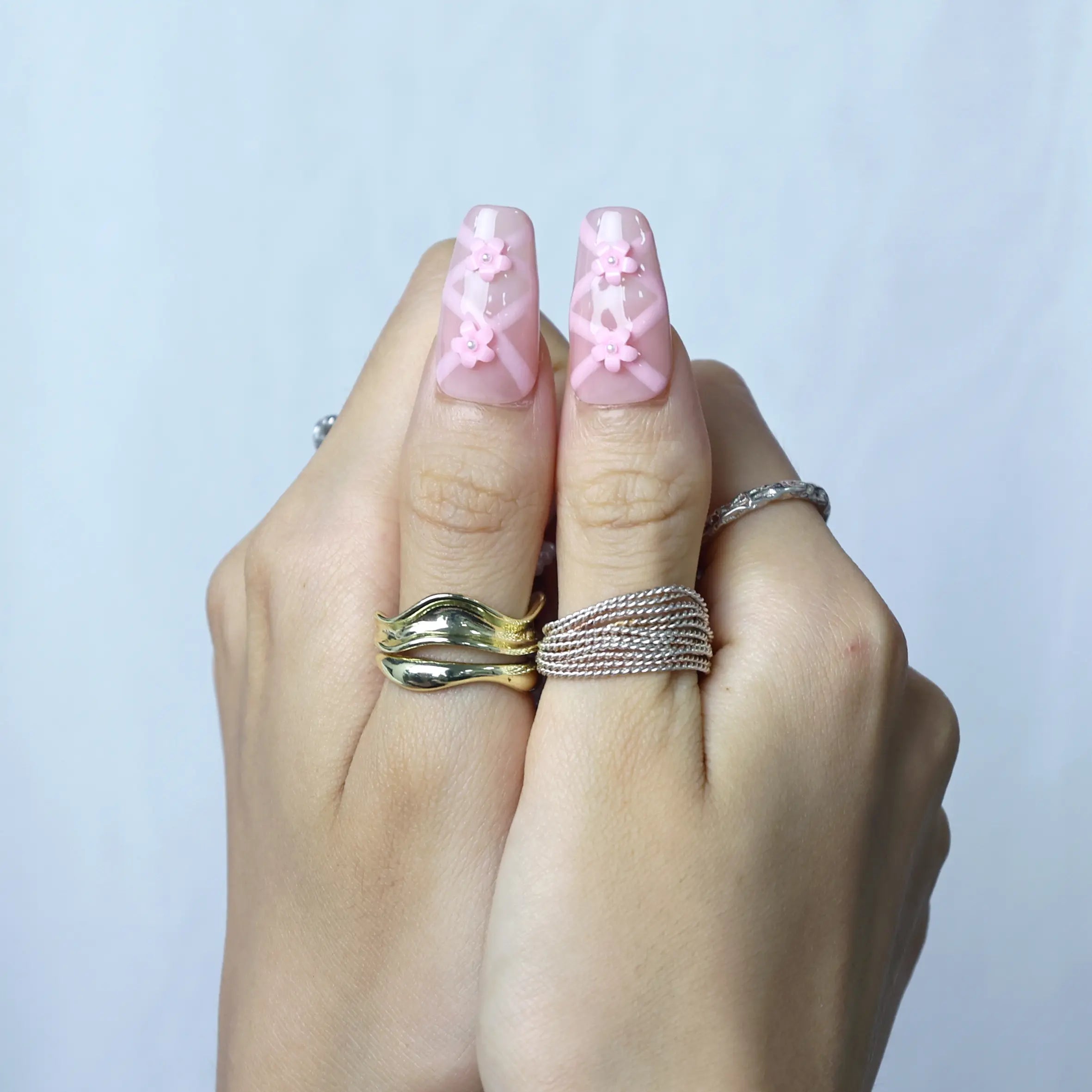 Romantic pink manicure featuring dimensional floral designs and elegant pearl accents