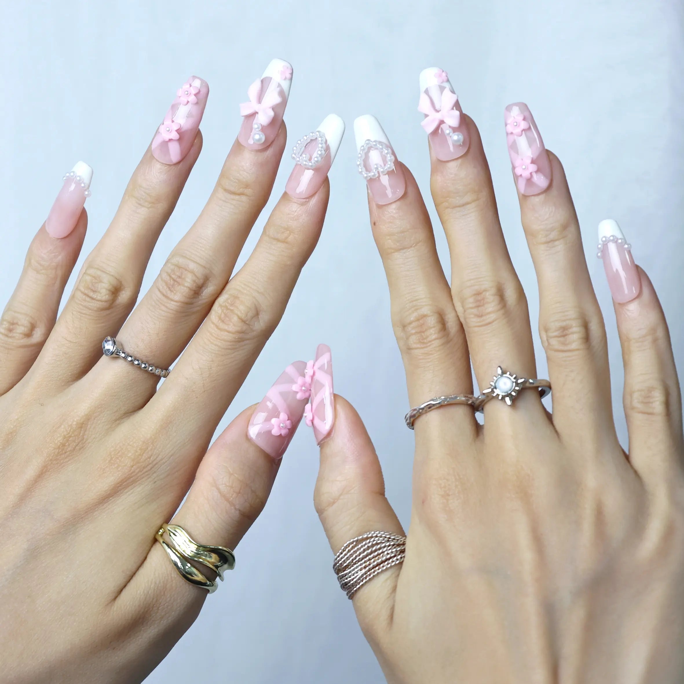 Sculptural nail art with pink base, 3D flowers, and pearlescent embellishments in coffin shape