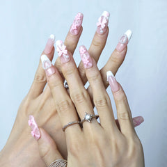Close-up of glossy pink press-on nails with intricate floral art and soft pearl touches