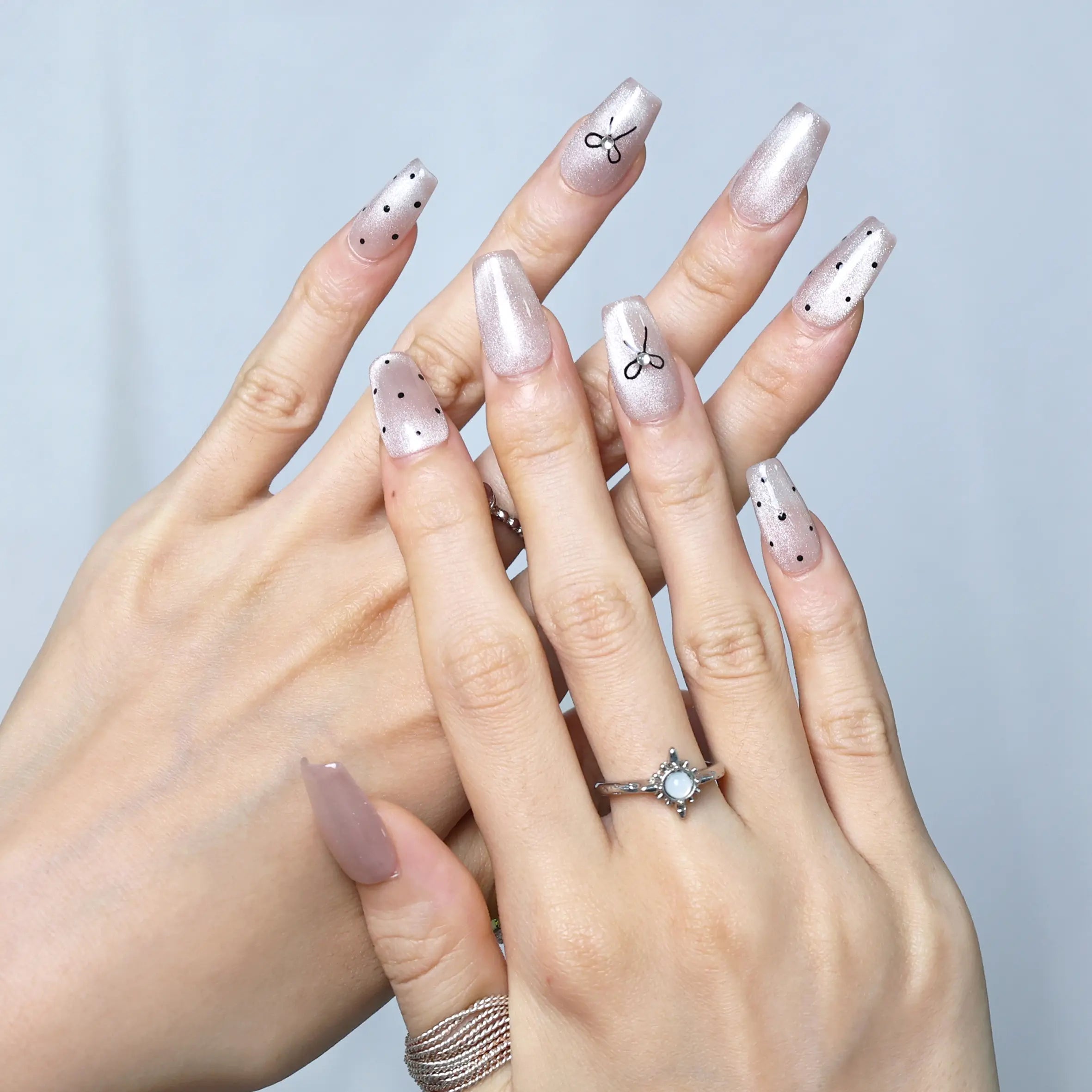 Close-up of blush press-ons featuring metallic bow accent