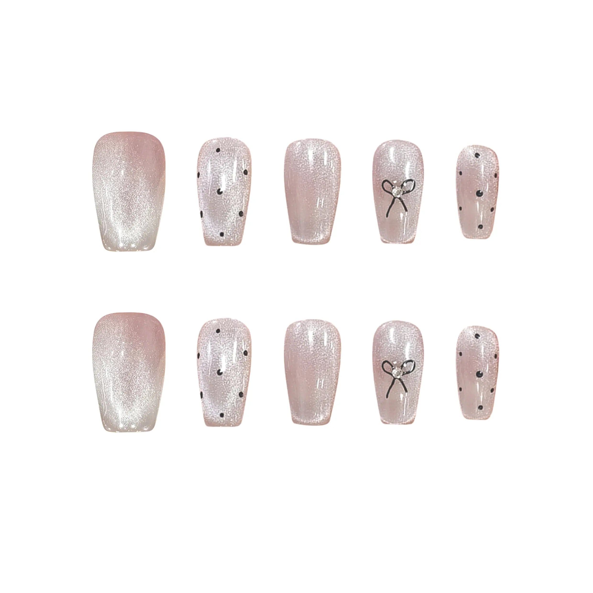 Blush pink press-on nails with black polka dots, metallic bow accent, and squoval shape for an elegant, playful look.