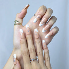 Hand model showing nude coffin press-on nails with silver stars and zodiac motifs
