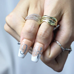 Nude base coffin nails with cosmic silver accents and fine zodiac art, styled on hand
