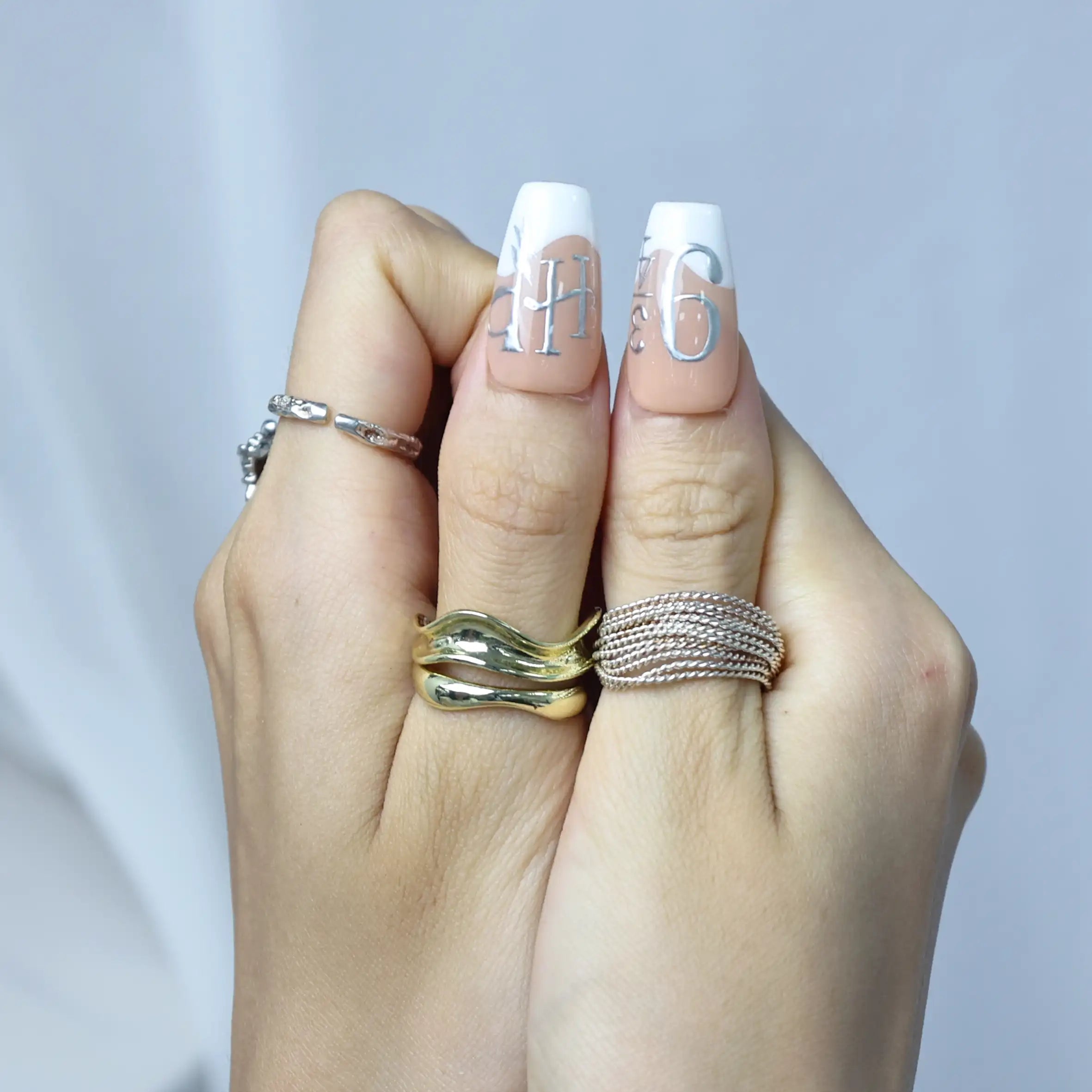 Elegant nude nails with astrology-inspired details and subtle silver stars, worn by model
