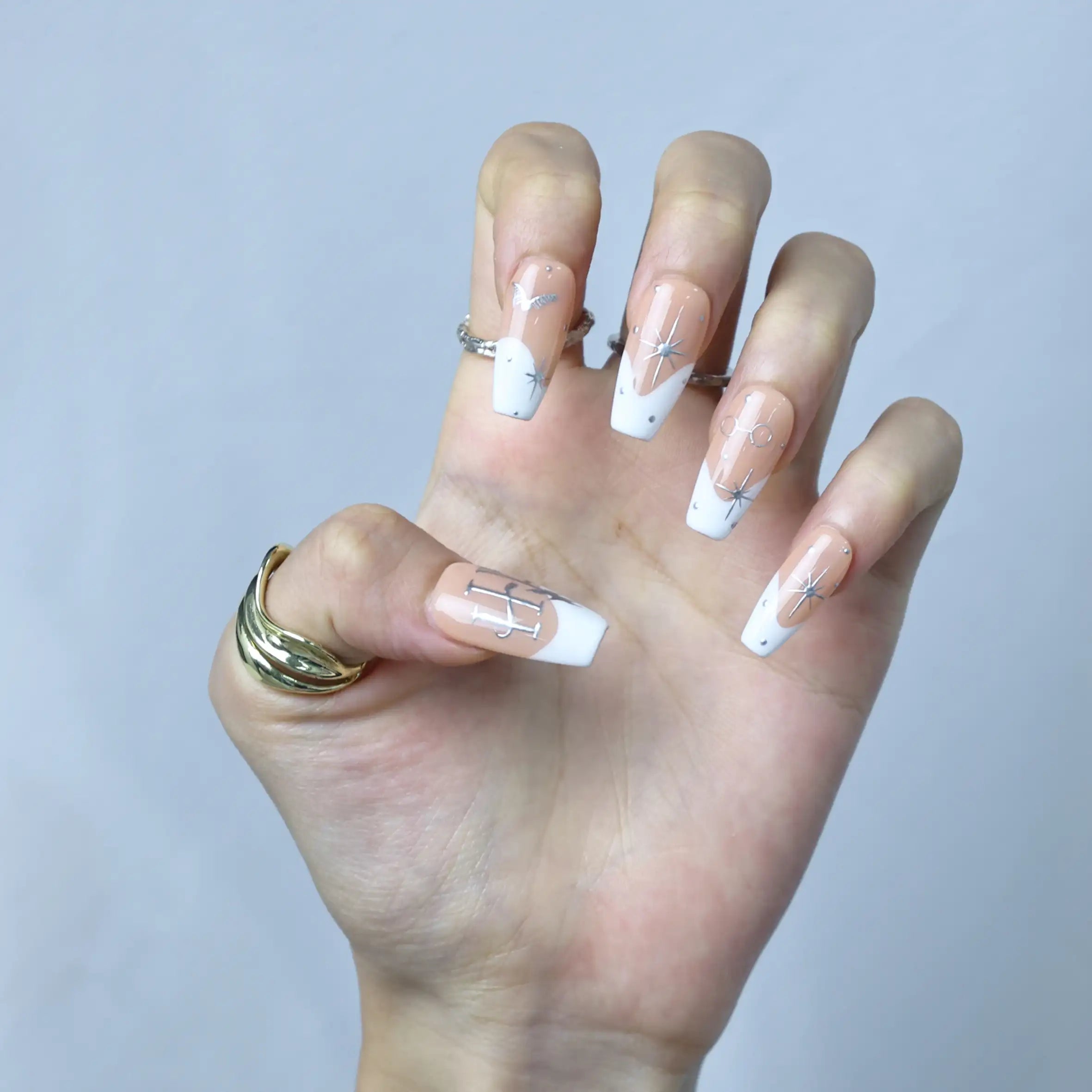 Stylish nude coffin nails with hand-drawn zodiac signs and constellation-like glitter
