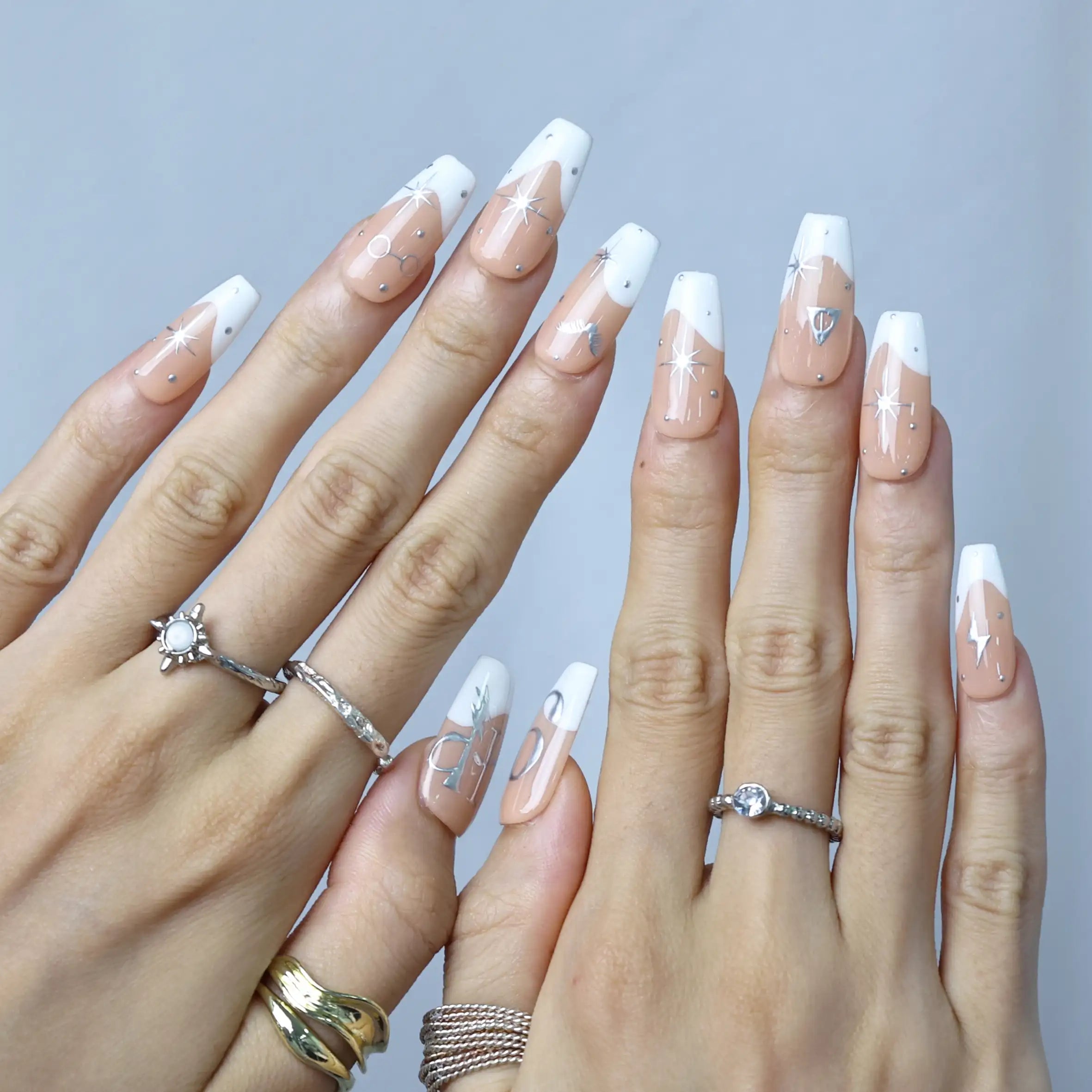 Detailed view of celestial press-on nails with silver star clusters and nude matte finish