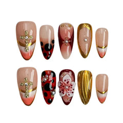 Medium almond red press on nails with gold foil accents and 3D floral designs.