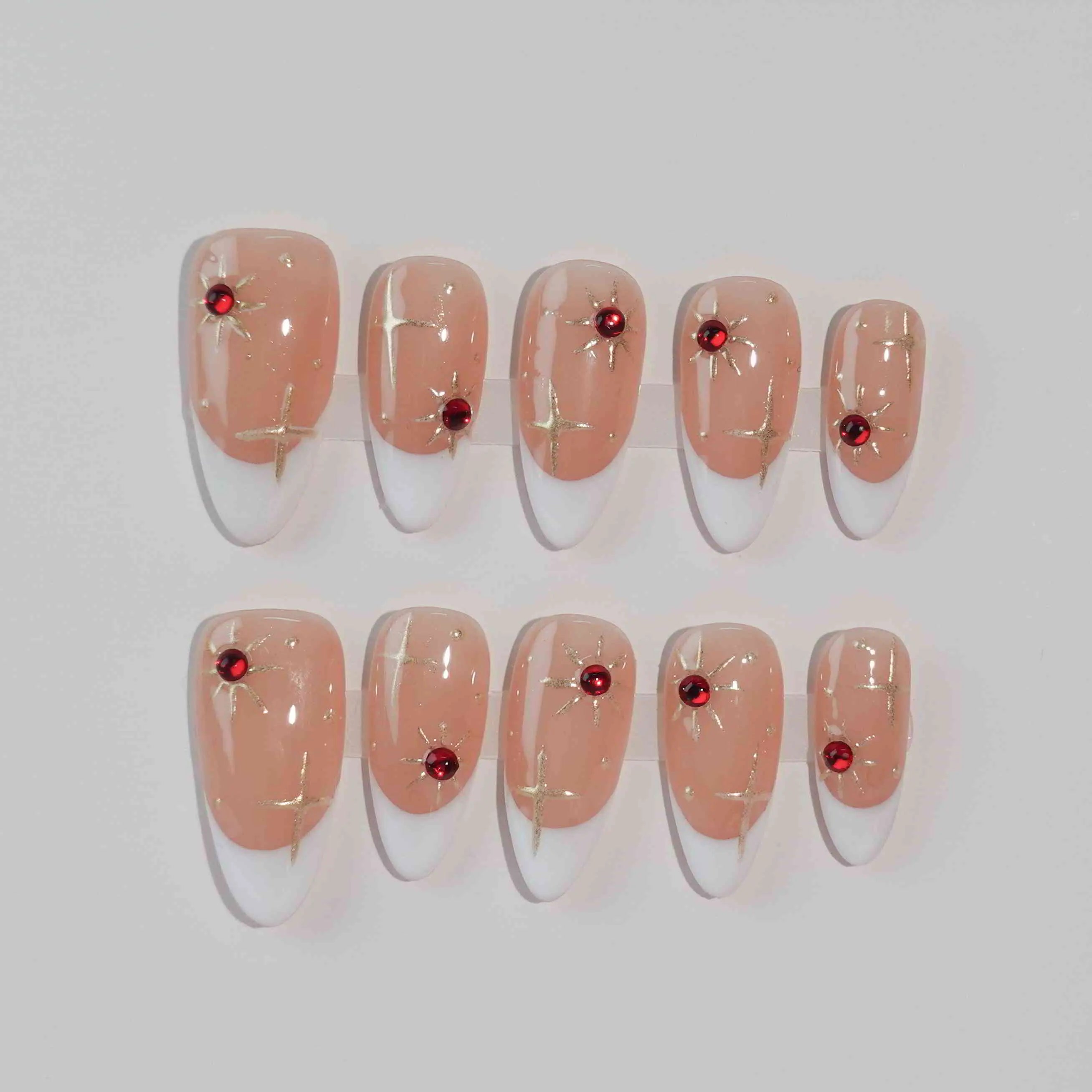 Semi-transparent red press on almond nails with scattered gemstone accents.