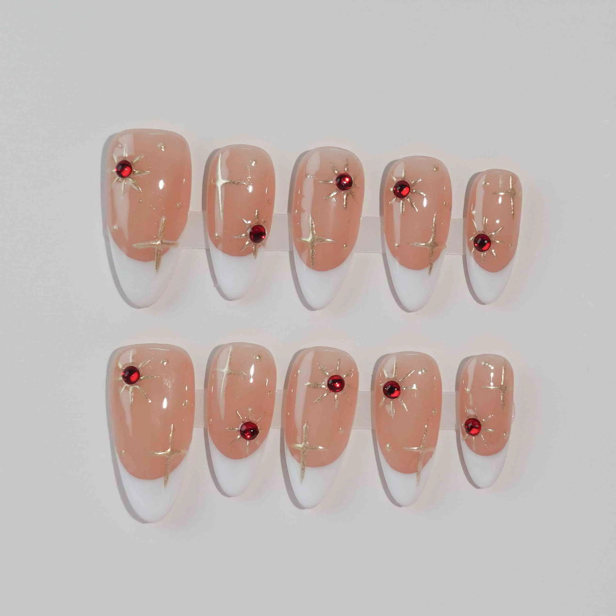 Semi-transparent red press on almond nails with scattered gemstone accents.