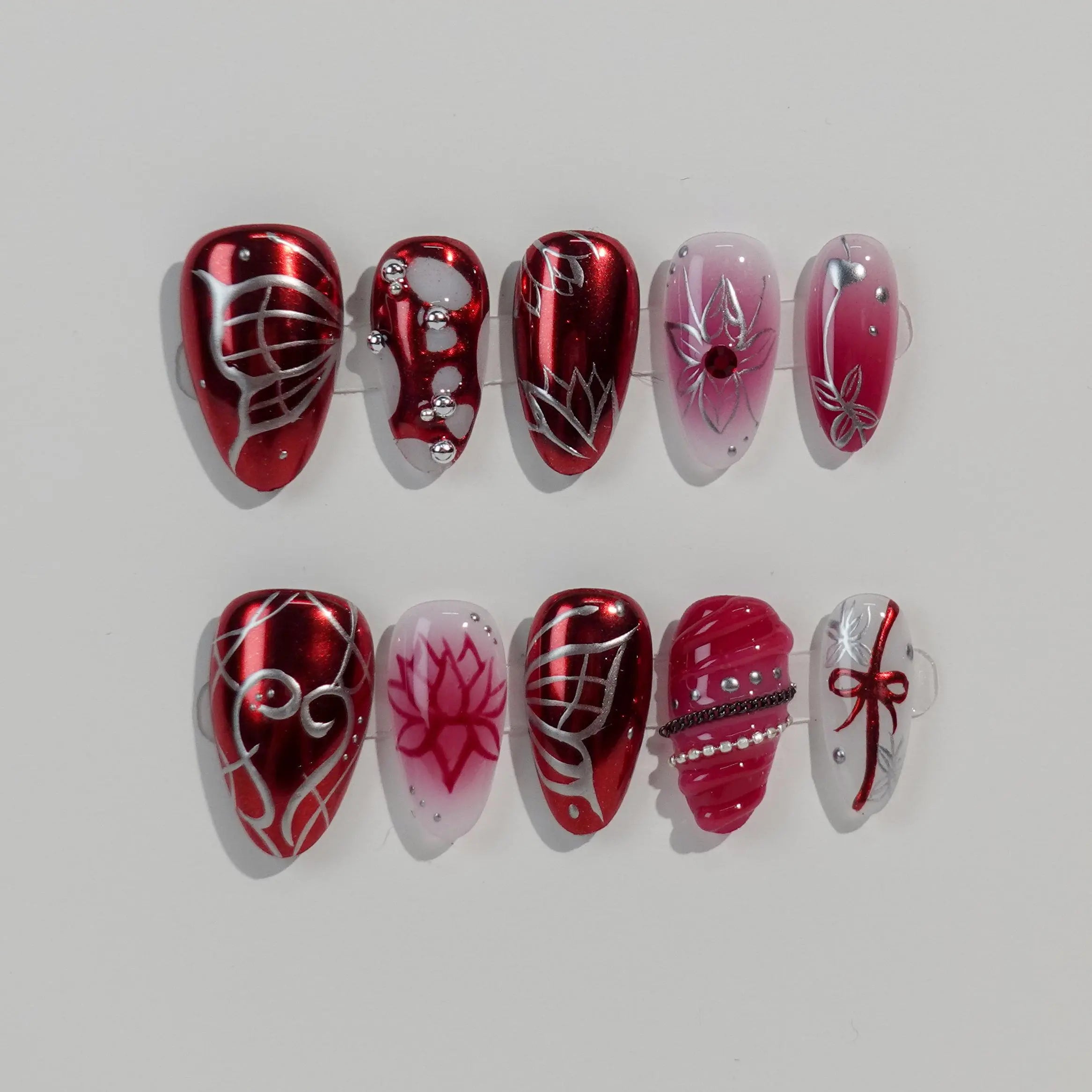 Almond-shaped red press on nails with glitter, gems, and bold line art, ideal for festive or night-out looks.
