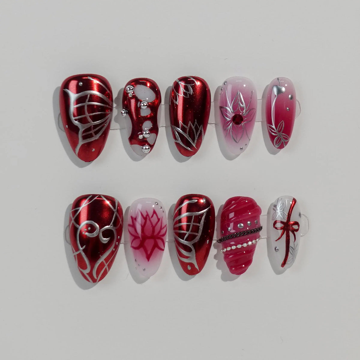 Almond-shaped red press on nails with glitter, gems, and bold line art, ideal for festive or night-out looks.