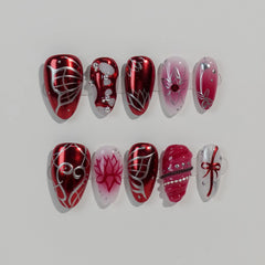 Almond-shaped red press on nails with glitter, gems, and bold line art, ideal for festive or night-out looks.