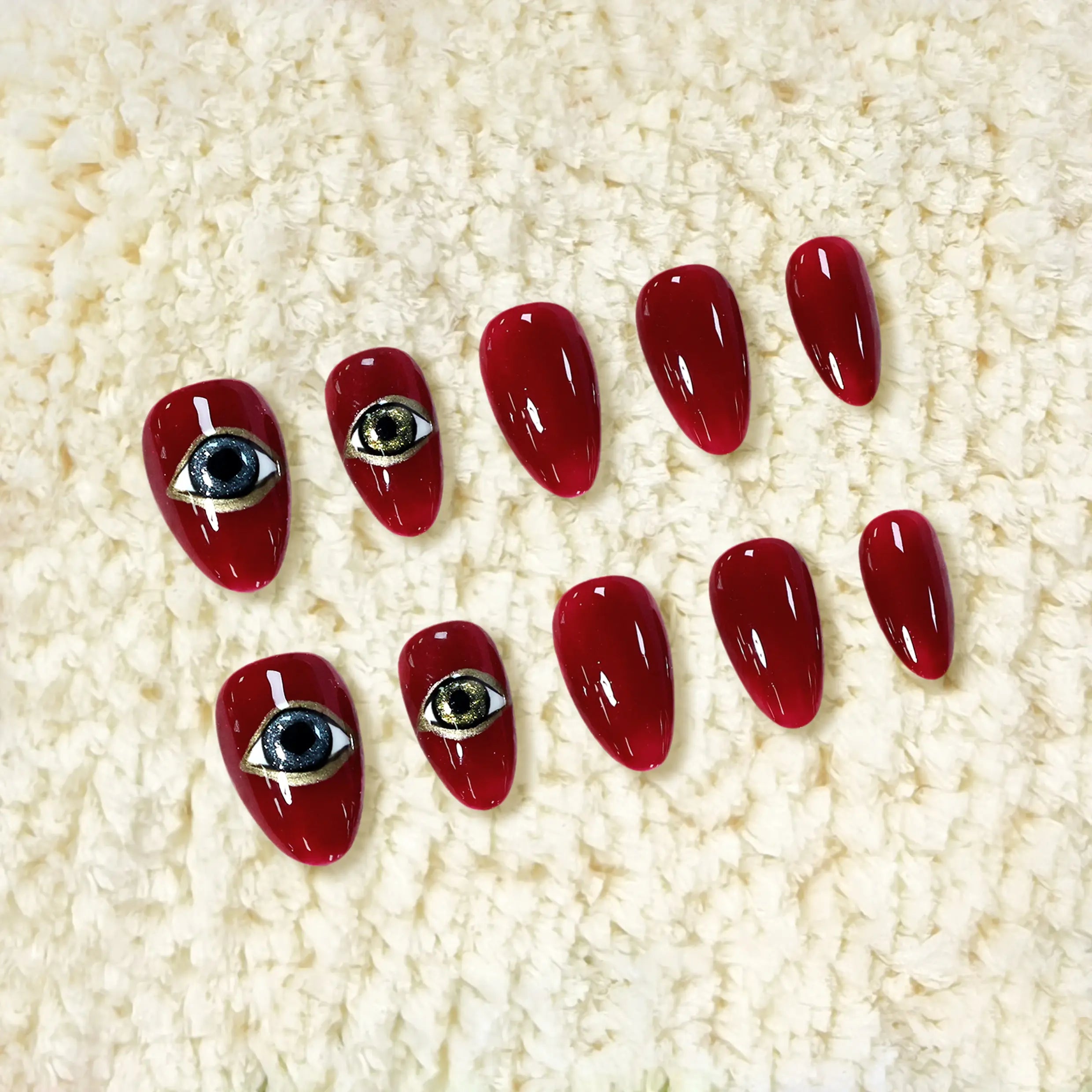 Short almond red press-on nails with glossy crimson finish, gold and black eye design for a mystical, bold aesthetic.