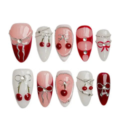 Medium red almond press on nails with cherries, white bows, and heart accents for soft girl aesthetic.