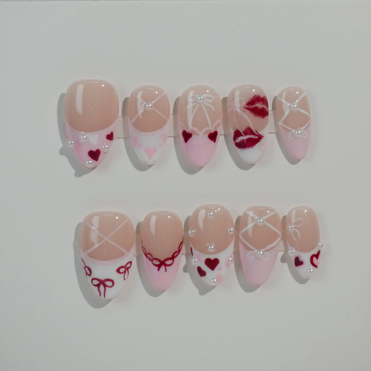 Pink almond press on nails with nude tones, heart patterns, and lace details—perfect for Valentine's Day.