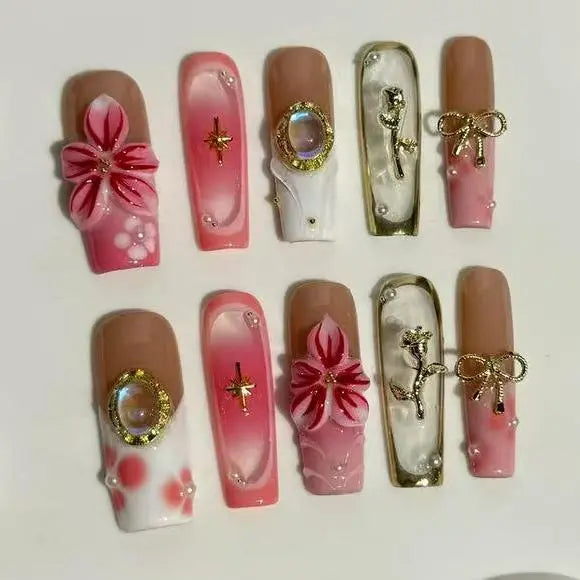Long pink and nude ombré press on nails decorated with flowers, pearls, and gold accents.
