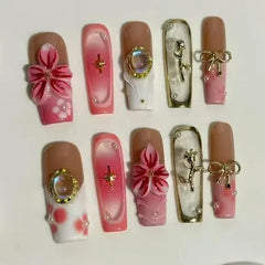 Long pink and nude ombré press on nails decorated with flowers, pearls, and gold accents.
