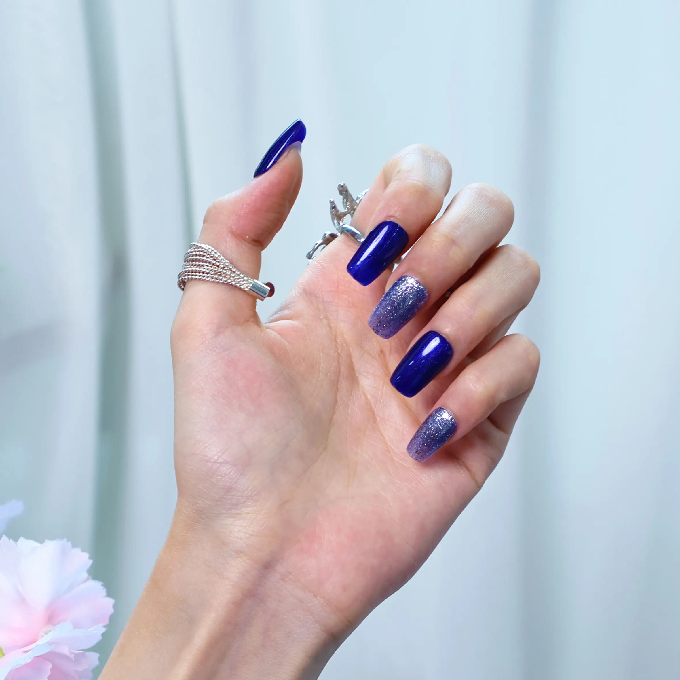 Elegant navy blue press-on nails with shimmering silver flecks, shown from side angle