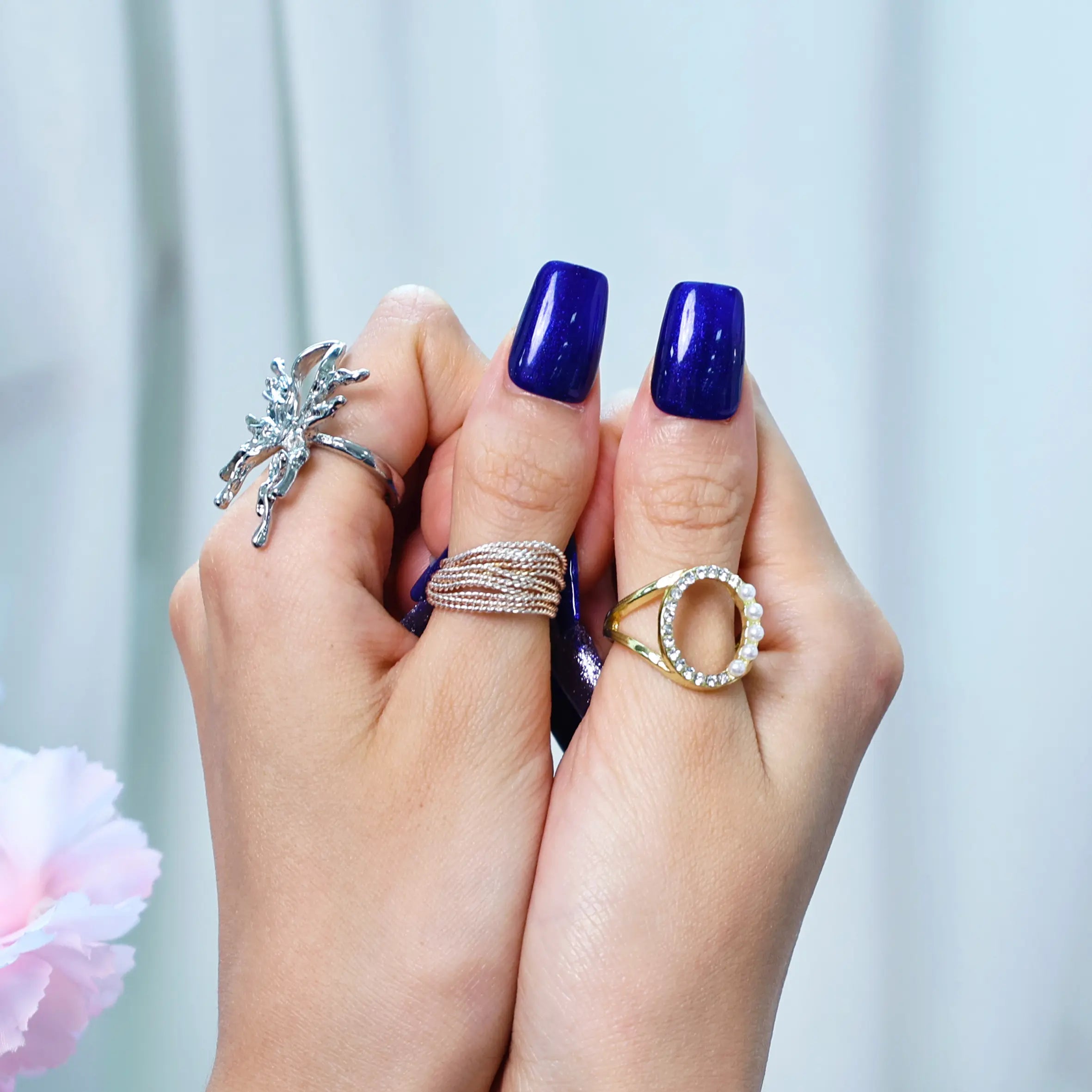 Lifestyle shot of royal sparkle nails styled with rings and soft lighting
