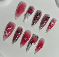 Long red and pink press on nails with floral branch designs and wing accents.