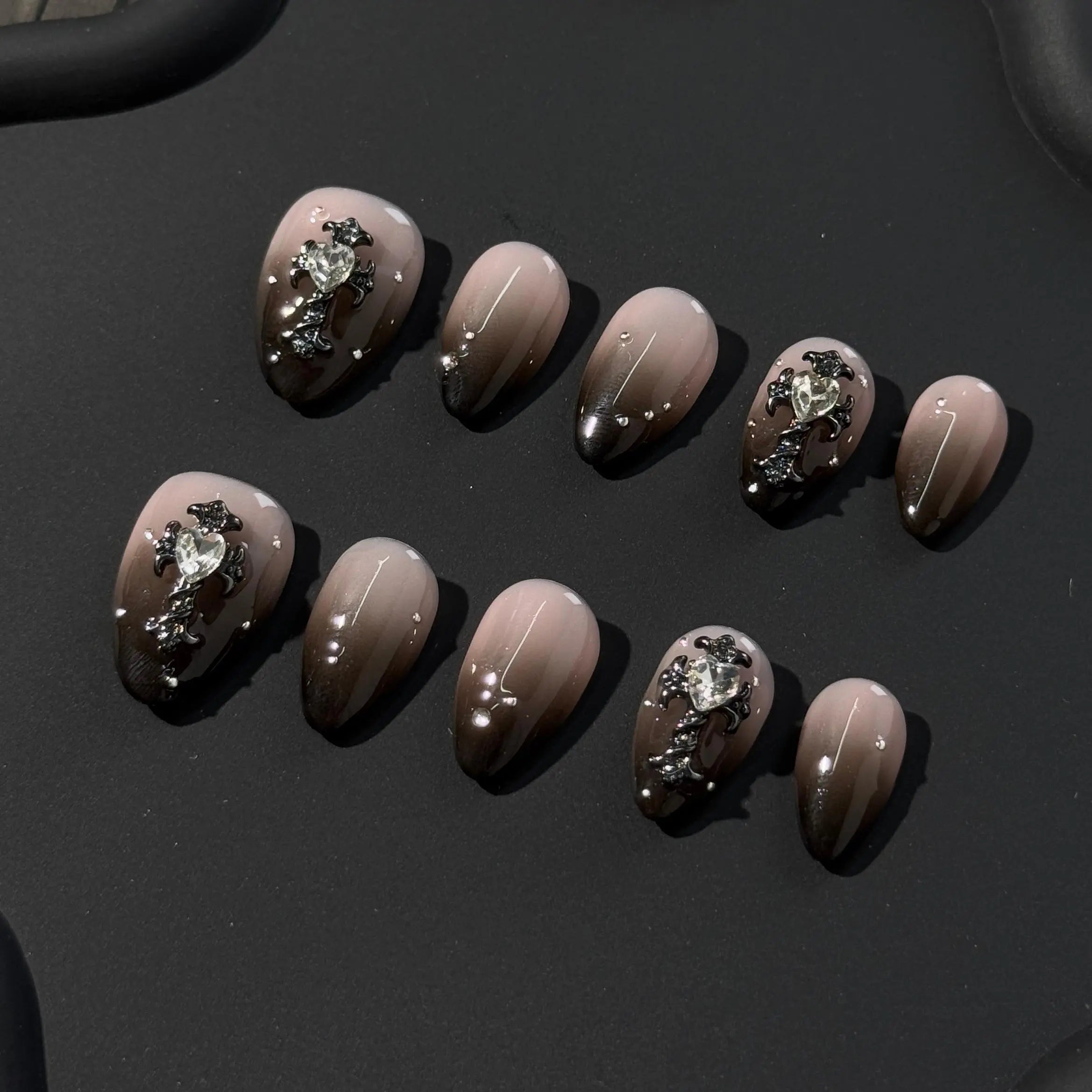 Elegant short almond press on nails in nude and espresso tones with rhinestone accents.