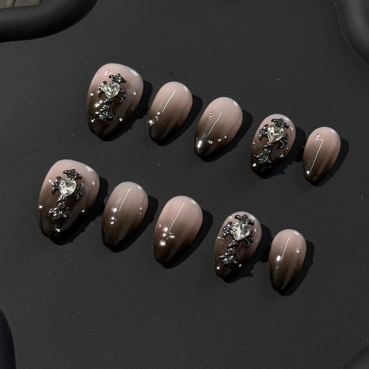 Elegant short almond press on nails in nude and espresso tones with rhinestone accents.