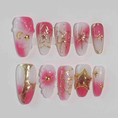 Pink ombré almond press-on nails featuring metallic gold star accents and a shimmering finish, handmade for special occasions.