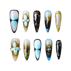 Stiletto-shaped black press on nails with gold-foiled petals and glowing turquoise accents.
