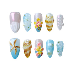 Almond-shaped summer press on nails with pearly seashell finishes, starfish accents, and pink tropical flowers.