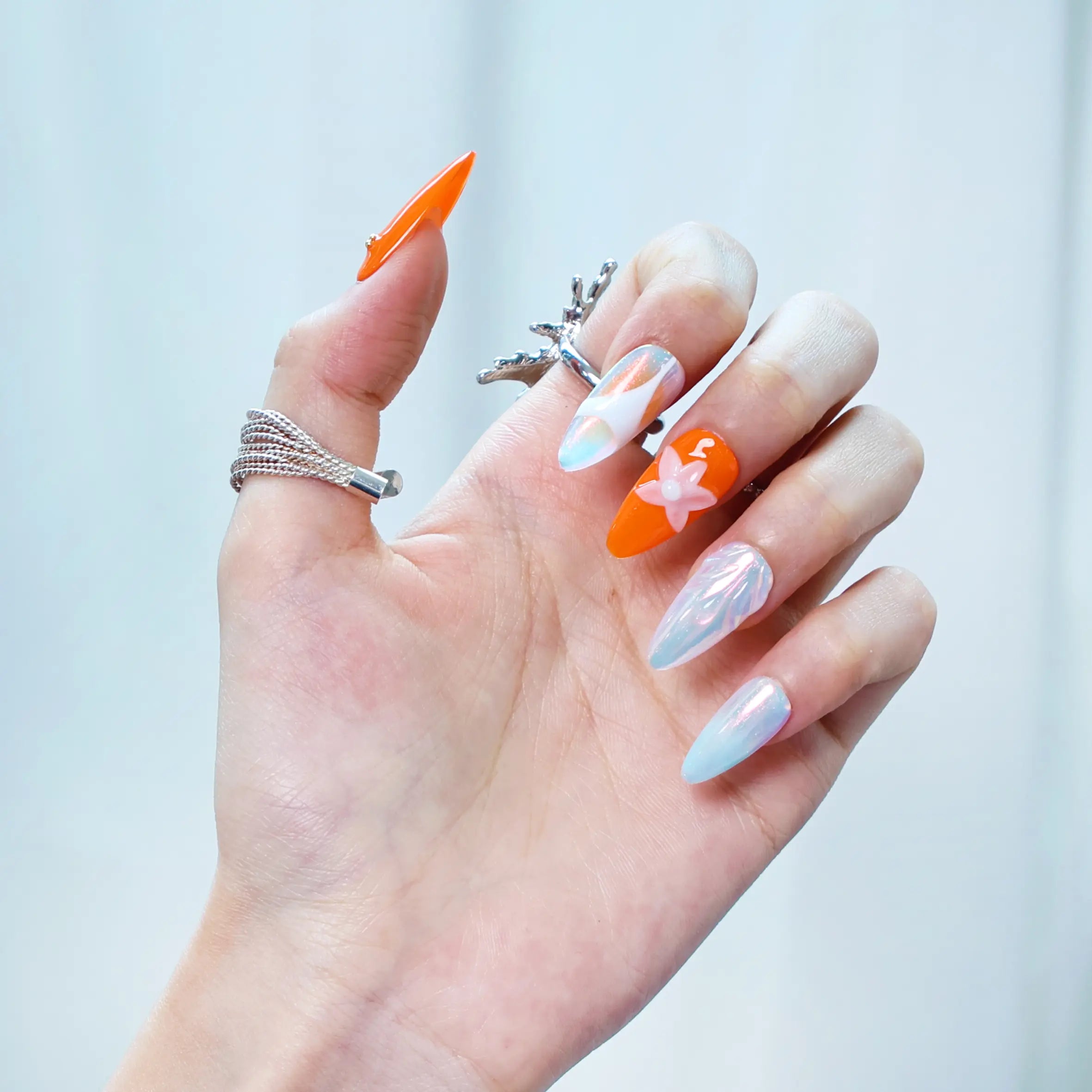 Close-up of blue and orange gradient nails featuring seashell-inspired pearls and starfish charms