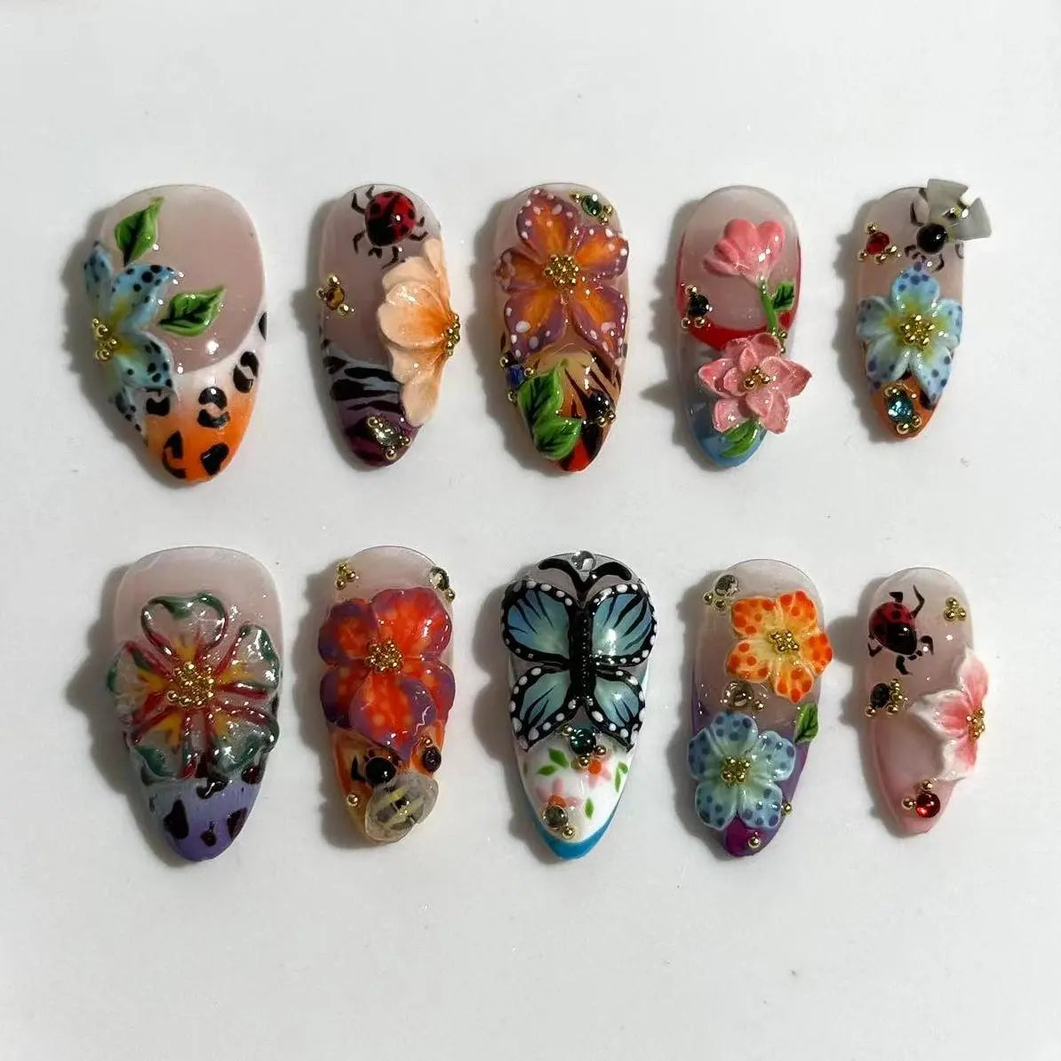 Almond summer nails with coral, tangerine, blue tones and 3D pink floral accents.