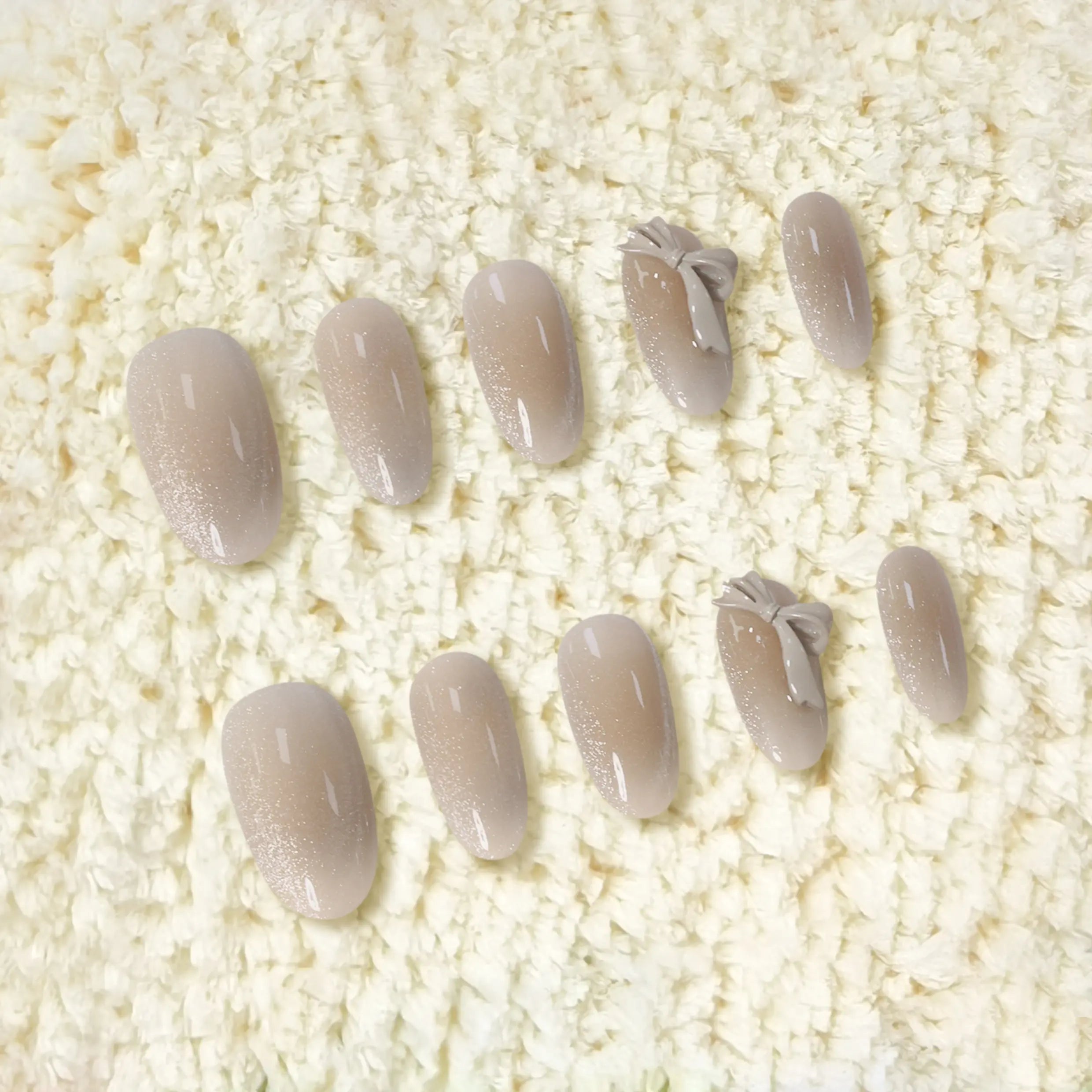 Medium oval nude press-on nails with 3D bows and subtle glitter accents, perfect for summer elegance and daily glam.