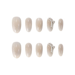 Medium oval nude press-on nails with 3D bows and subtle glitter accents, perfect for summer elegance and daily glam.