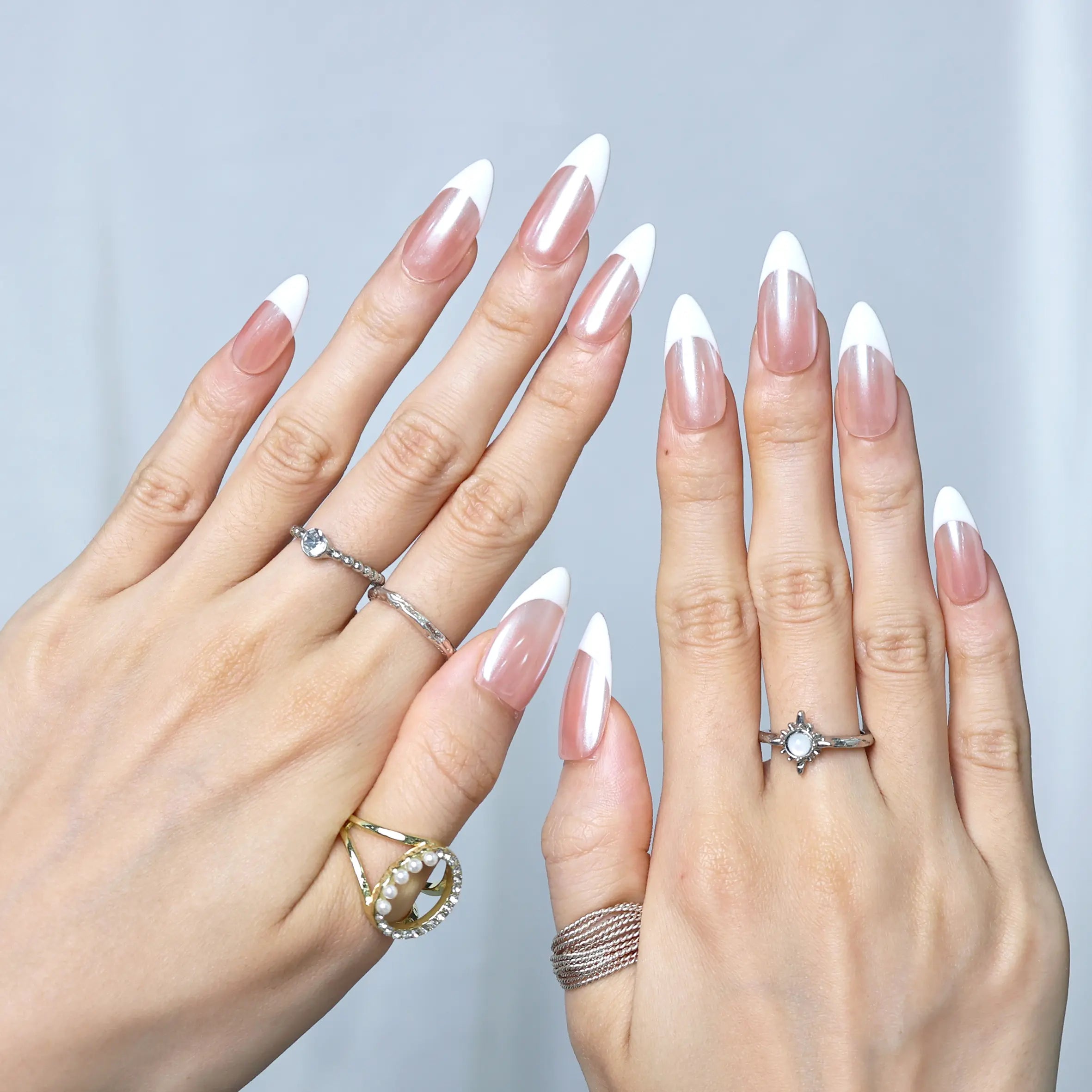 Glossy French tip press-ons worn on model’s hand, blending nude polish with bold white tips