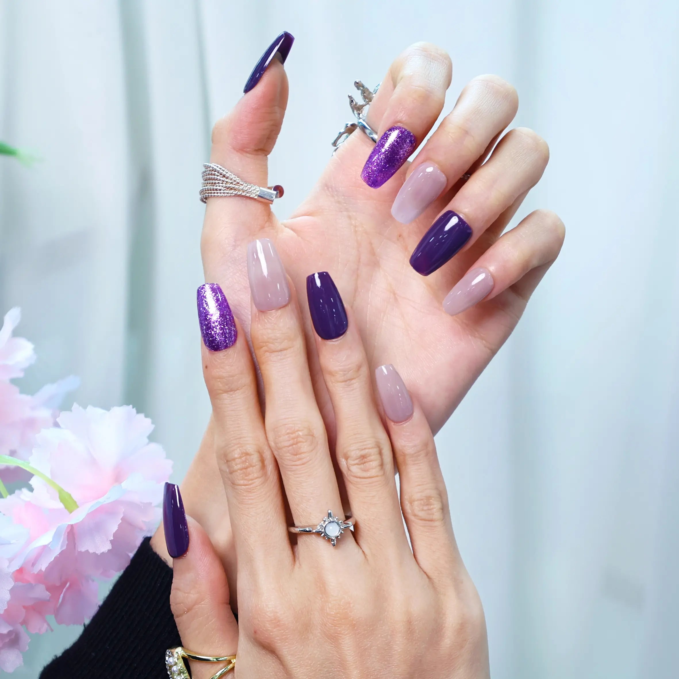 Close-up of Violet Dream press-on nails on hand with floral background