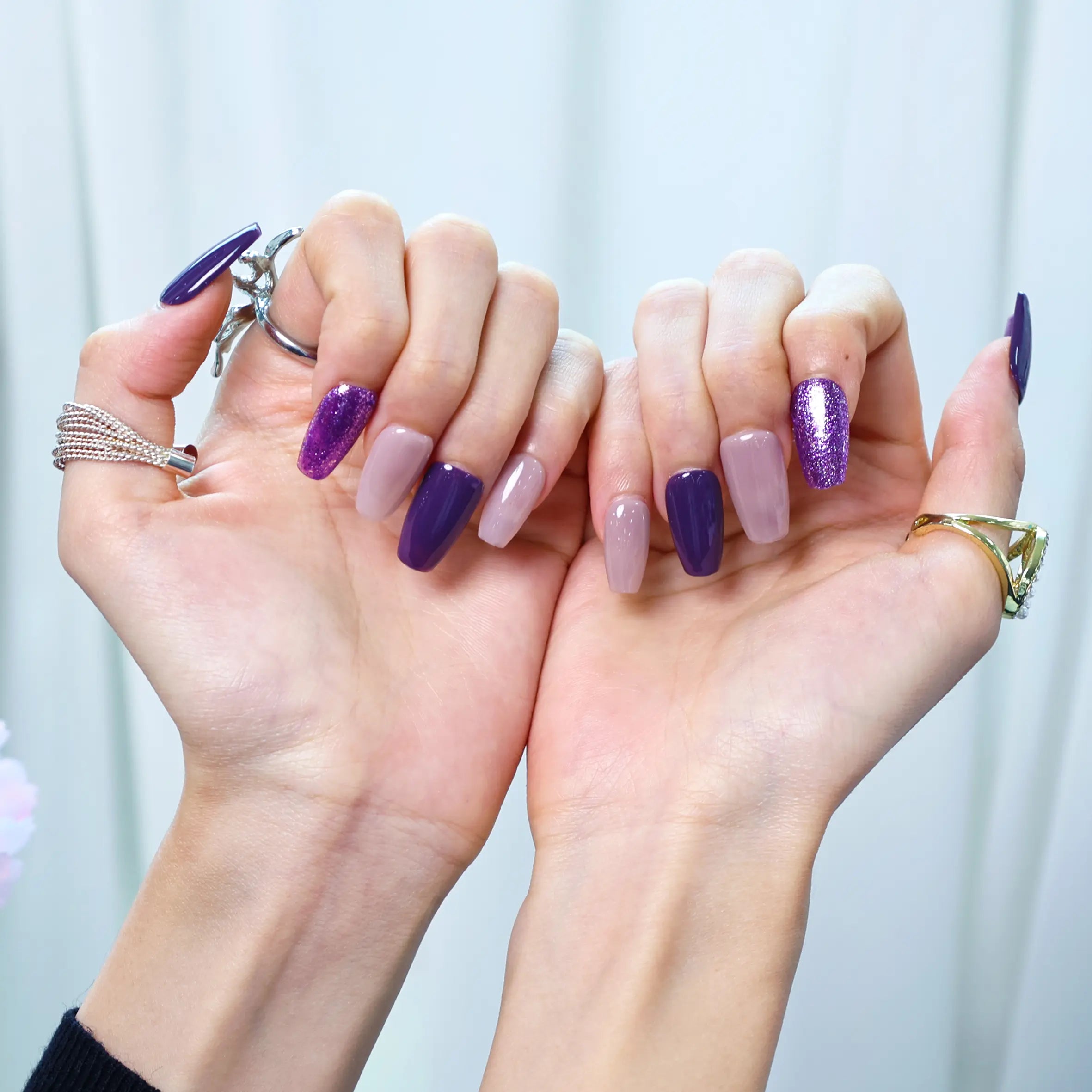 Summer-style press-on nails with violet and shimmer finish in a floral setup