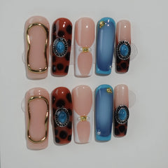 Coffin press on nails with leopard print, rose gold accents, and nude base—perfect for bold summer nail looks.