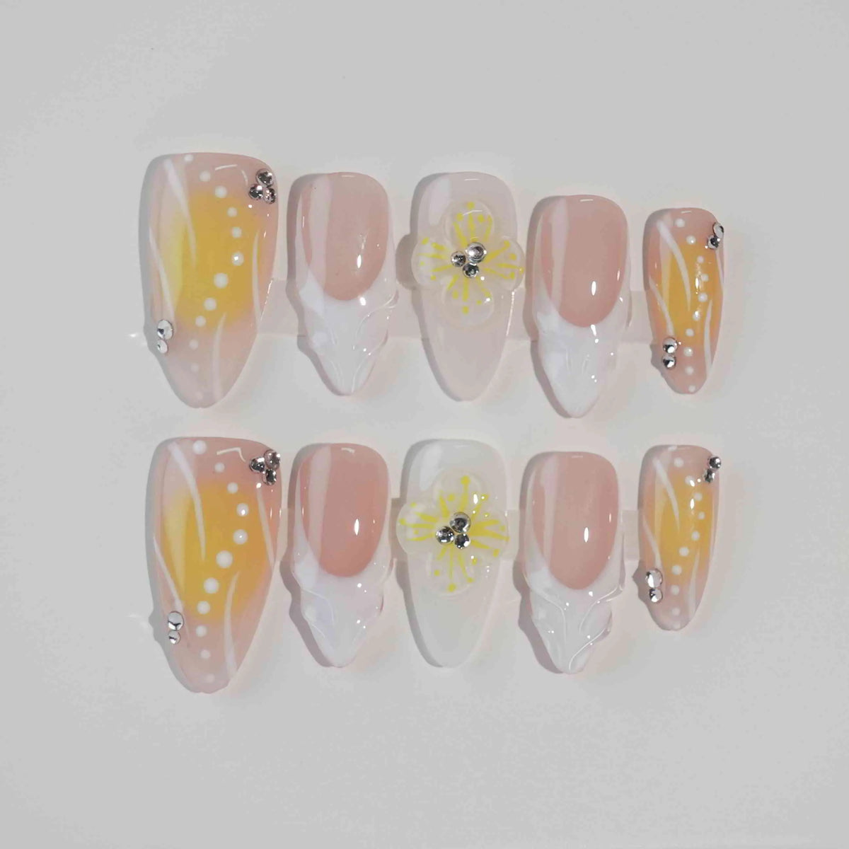 Almond press on nails in sunshine yellow with playful polka dots and pink floral details.