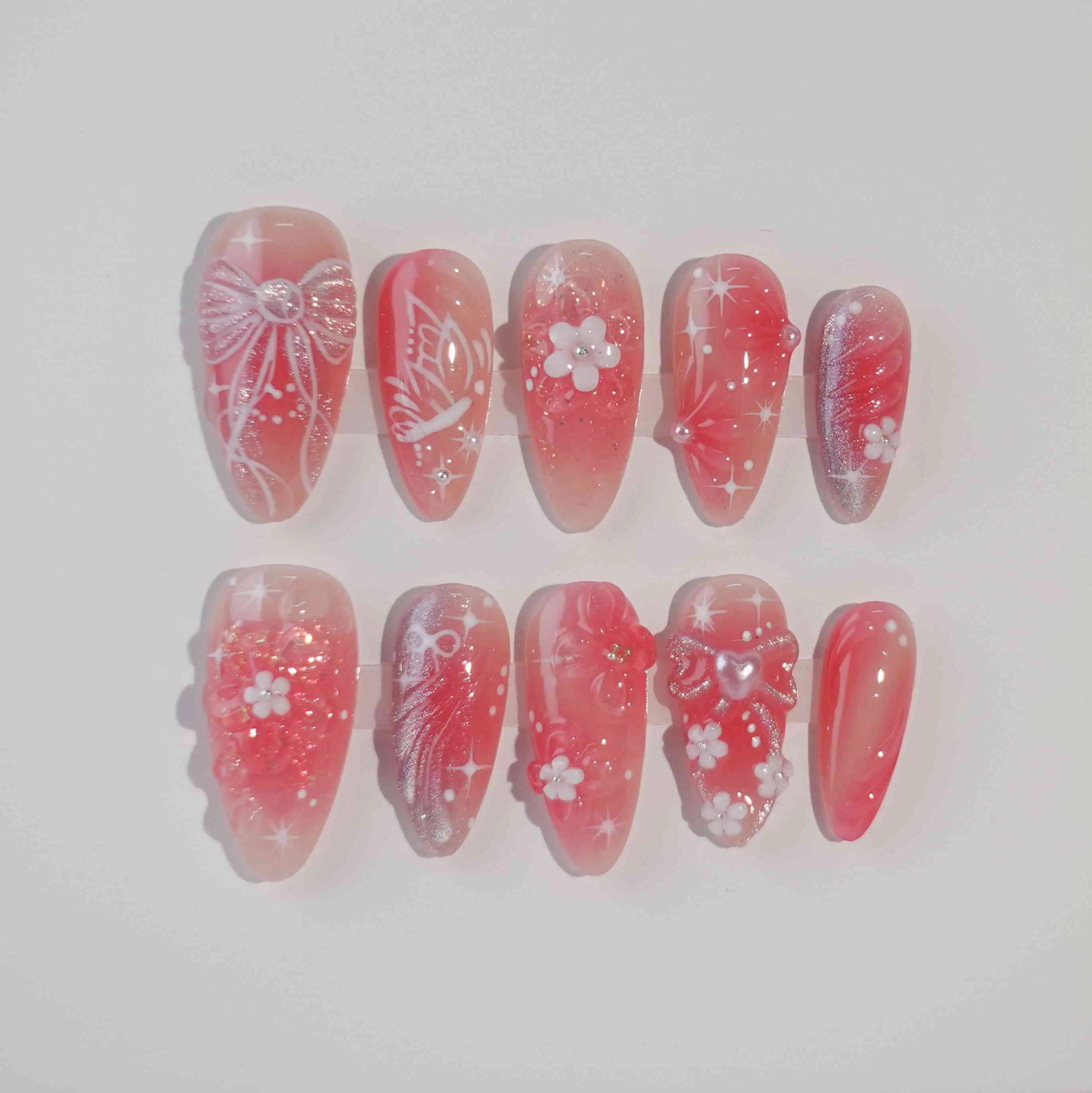 Pink and red ombré almond press-on nails with 3D cherry blossoms, sparkles, and tiny bow accents—romantic and handmade.